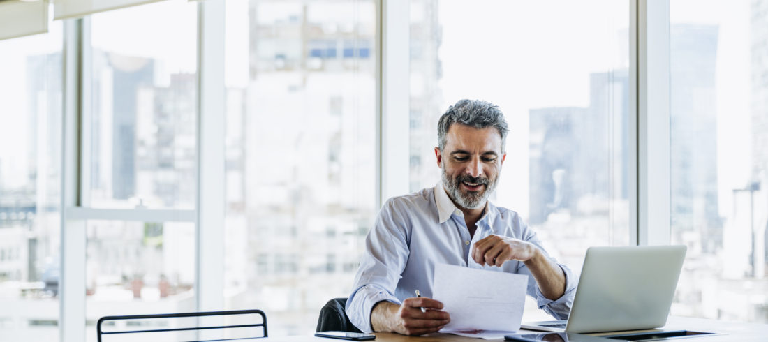 Male executive smiling while reading document in office